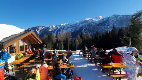 Skiers-and-snowboarders-taking-a-break-to-grab-a-drink-and-eat-in-Trentino,-Italy