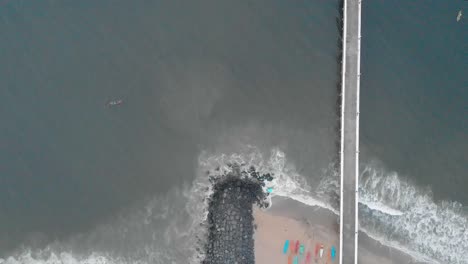 4k-Aerial-Crane-moving-Down-shot-of-a-Shipping-Port-Pier-on-a-Sunrise-with-monsoon-clouds-covered-near-Rock-Beach-shot-with-a-drone,-Pondicherry,-India