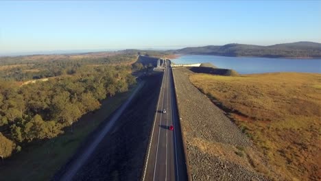 Aerial-shot-flying-along-the-road-towards-Wivenhoe-dam,-with-the-sun-at-a-low-angle,-on-Lake-Wivenhoe-in-Queensland's-Somerset-Region