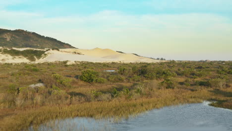 Low-aerial-cinematic-view-of-sandbanks-lagoons-and-sand-dunes-at-Praia-Da-Joaquina,-Florianopolis-city,-Santa-Catarina,-Brazil