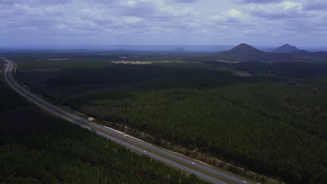 Aerial-shot-of-Bruce-Highway-heading-to-Sunshine-Coast,-surrounded-by-green-trees