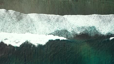Beautiful-sea-texture-on-dark-green-colors-with-dramatic-waves-foaming-over-seashore-of-tropical-island-seen-from-above,-copy-space