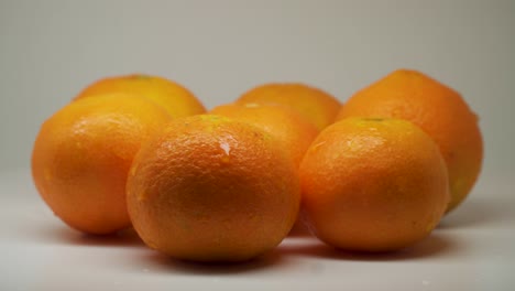 Siete-Naranjas-Carnosas-Con-Gotitas-De-Agua-Encima-De-La-Mesa---Primer-Plano