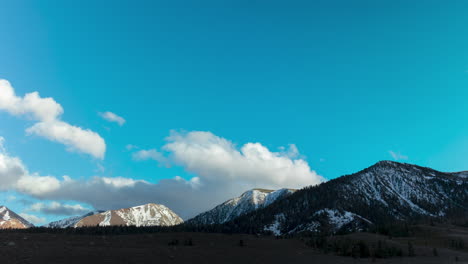 Verschneite-Bergkette-Mit-Rollenden-Wolken-Und-Blauem-Himmel
