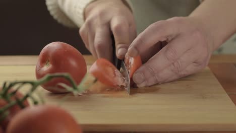 Hands-cutting-fresh-vine-tomatoes-on-chopping-board-close-up-shot
