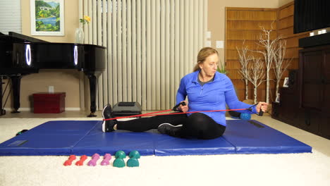 Mature-woman-exercising-on-mat-pulling-on-stretch-bands,-static-locked-off-tripod