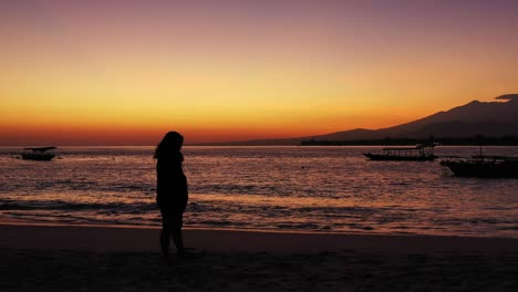Silhouette-Einer-Frau-Mit-Ausgestreckten-Händen-Am-Tropischen-Sandstrand-Während-Des-Violetten-Sonnenuntergangs