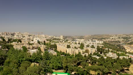 Vuelo-Aéreo-Sobre-El-Barrio-Suburbano-De-Jerusalén-En-Un-Día-Cálido,-árboles-Verdes-Que-Crecen-Entre-Los-Edificios