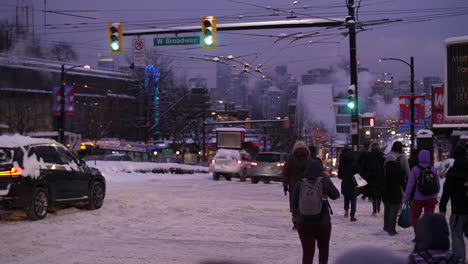 Verschneite-Kreuzung-Mit-Vorbeifahrenden-Autos-Und-Vielen-Fußgängern