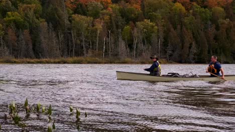 Two-White-Men-Canoe-past-on-Windy-Lake-of-Fall-Tree-Colors,-Fixed-Wide