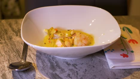 Pouring-Nutritious-Seafood-Chowder-To-A-White-Bowl-On-The-Table-Using-A-Ladle---close-up