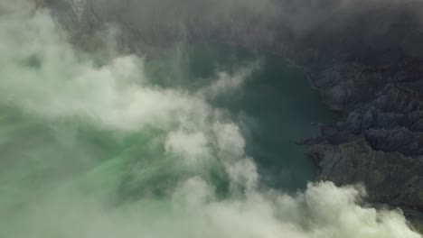 Aerial-Pan-Down-of-Acidic-Lake-With-Smoke-Inside-a-Volcano