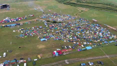 Luftaufnahme-Von-Mehrfarbigen-Zelten,-Die-Auf-Einem-Musikfestival-Aufgestellt-Wurden,-Mit-Blick-Auf-Freizügige-Felder-Und-Die-Umgebung
