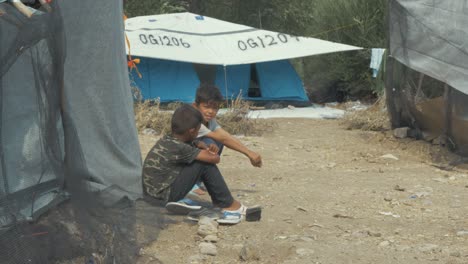 Zwei-Kinder-Im-Flüchtlingslager-Moria-Sitzen-Zusammen-Und-Unterhalten-Sich-Vor-Dem-Zelt