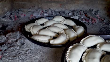 Uncooked-traditional-Argentinian-empanadas-inside-a-clay-oven-surrounded-by-burning-ashes