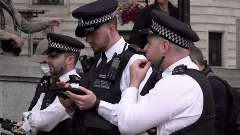 A-police-officer-uses-a-computer-tablet-during-a-stop-and-search-of-environmental-activists-attending-a-Beyond-Politics-Party-protest-on-Trafalgar-Square