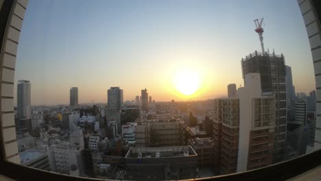 Ultra-wide-time-lapse-of-the-Osaka-skyline-buildings-sun-setting,-Unizo-hotel-sign-visible-below,-locked-speed-up-shot