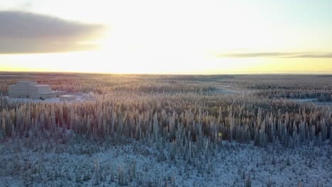 Aerial,-tracking,-drone-shot,-over-snowy-forest,-revealing-the-HAARP-Alaska-facility,-at-sunset-on-a-cold-and-sunny,-winter-day,-in-Gakona,-USA