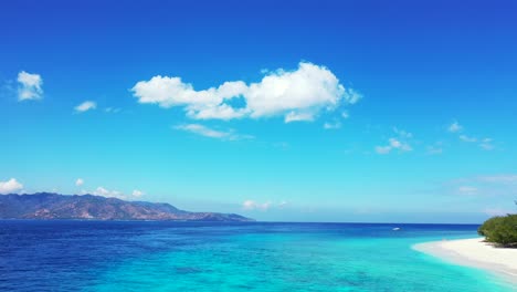 Vivid-colors-of-amazing-seascape-with-bright-blue-sky-with-static-clouds-hanging-over-blue-turquoise-sea-between-two-tropical-islands-in-Indonesia