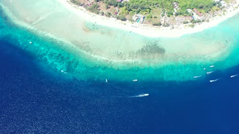 Farbenfrohe-Meereslandschaft-Mit-Türkisblauem-Meerwasser-Rund-Um-Den-Weißen-Sandstrand-Einer-Tropischen-Insel,-Boote,-Die-An-Der-Wunderschönen-Küste-In-Indonesien-Segeln