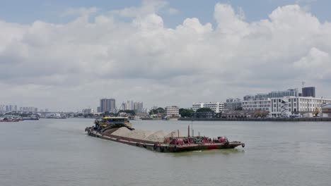 Chinese-river-barge-vessel-full-loaded-with-sand-bulk-cargo-underway-on-Zhujiang-River,-on-a-cloudy-day