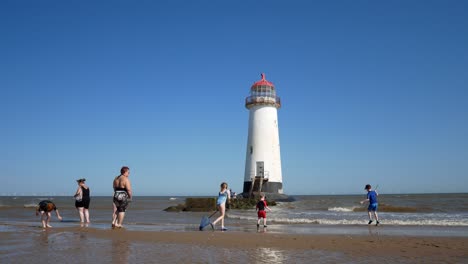 Tourist-family-playing-at-Landmark-abandoned-Ayr-lighthouse-sandy-beach-coastline