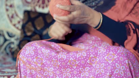 Indian-woman-roll-the-red-thread-into-a-ball-and-preparing-it-for-knitting