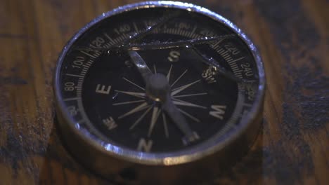 Compass-Arrow-Moving-On-Different-Direction-While-Lying-On-The-Wooden-Table---Close-Up-Shot