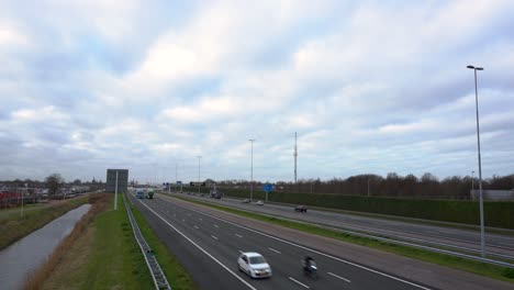 Vehicles-travelling-on-Dutch-highway,-camera-tilt-up,-from-flyover-bridge