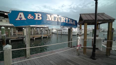 Wide-Shot-of-Marina-Sign-With-Boats-Docked-in-Harbor-in-Background-in-Key-West,-Florida