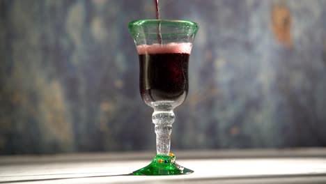 Seamless,-looping-clip-of-red-wine-pouring-into-a-rustic-glass-with-blue-background