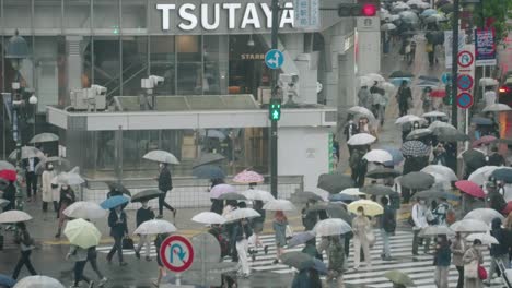 Gran-Número-De-Personas-Con-Paraguas-Cruzan-El-Cruce-De-Shibuya-En-Un-Día-Lluvioso-En-Tokio,-Japón