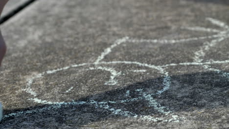 CLOSE-UP-Of-Young-Boys-Hand-Drawing-A-Cat-On-Cement-Driveway