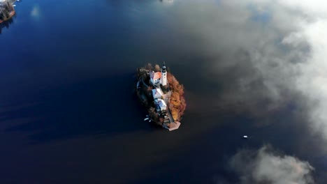 Die-Kamera-Fliegt-über-Die-Insel-Bleder-See,-Während-Sie-über-Die-Insel-Schwenkt-Und-Ein-Traditionelles-Plenta-Boot-Auf-Die-Insel-Zurudert