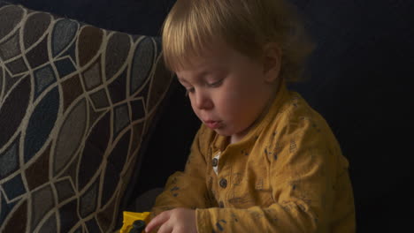 Kleinkind-Sitzt-Auf-Einem-Sofa-Und-Spielt-Mit-Einem-Spielzeuglastwagen