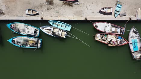 Aerial-view-looking-straight-down-and-camera-sliding-to-the-right-showing-small-wooden-fishing-boats-in-a-harbor-in-Mexico