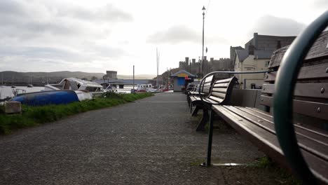 Empty-harbour-wooden-benches-on-Conwy-waterfront-marina-during-covid-lockdown-dolly-low-angle-left