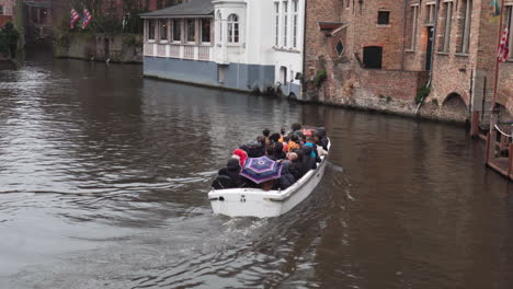 Wide-shot-of-tourists-cruising-by-boat-through-a-beautiful-historical-canal-Of-Bruges-In-Belgium