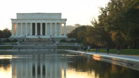 Lincoln-Memorial-at-sunset-reflecting-in-pool-and-tourists,-Washington-DC