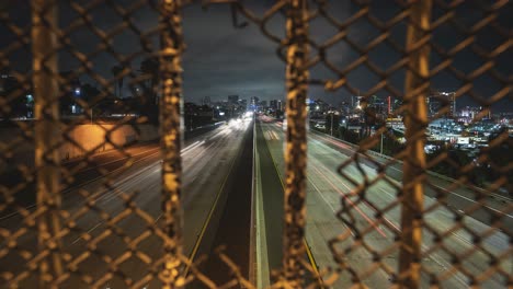 Timelapse-looking-through-fence-hole-at-traffic-from-San-Diego-city