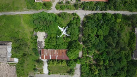Abandoned-old-airplane-in-the-middle-of-green-field,-aerial-top-down