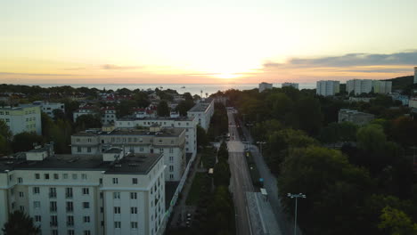 Marvelous-drone-ascends-from-and-empty-Polish-street-in-Gdynia-to-reveal-miraculous-orange-Sunset,-Aerial