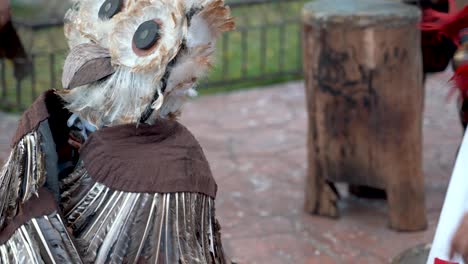 Extreme-closeup-of-a-Mayan-or-Aztec-dancer-in-a-bird-costume-with-feathers-and-large-orange-headdress-that-looks-like-an-owl