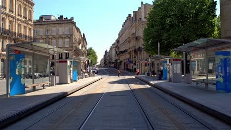 Hotel-de-Ville-and-Saint-Andrew-Cathedral-Tram-trolley-stop-with-few-people-during-the-COVID-19-pandemic,-Dolly-forward-shot
