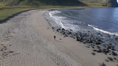 A-person-walking-over-a-secluded-beach-in-Lofoten,-Norway
