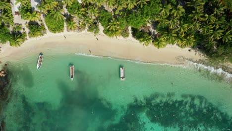 Wunderschöne-Fidschi-Insel,-Bestehend-Aus-Weißem-Sand-Und-Palmen,-Mit-Einem-Boot,-Das-Auf-Dem-Meer-Schwimmt,-Und-Touristen,-Die-Am-Ufer-Spazieren-Gehen---Luftaufnahme