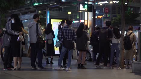 Koreaner-Mit-Schutzmasken-Warten-Nachts-An-Der-Bushaltestelle-Im-Bezirk-Gangnam-In-Der-Schlange,-Um-Den-Bus-Zu-Nehmen