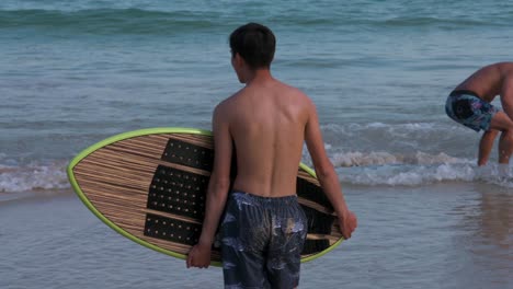 A-man-is-seen-with-his-surfboard-at-Shek-O-beach-in-Hong-Kong-as-public-beaches-reopening,-after-months-of-closure-amid-coronavirus-outbreak,-to-the-public