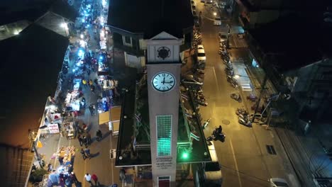 Aerial-Footage-of-The-Vietnamese-Memorial-Clock-Tower-in-Nakhon-Phanom-Province,-Thailand-Surrouned-by-Lively-Night-Walking-Street