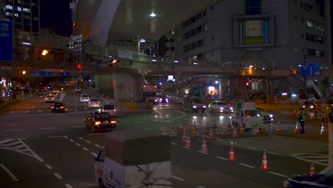 Traffic-Going-By-Underneath-Freeway-And-Pedestrian-Bridge-In-Shibuya,-Tokyo-At-Night